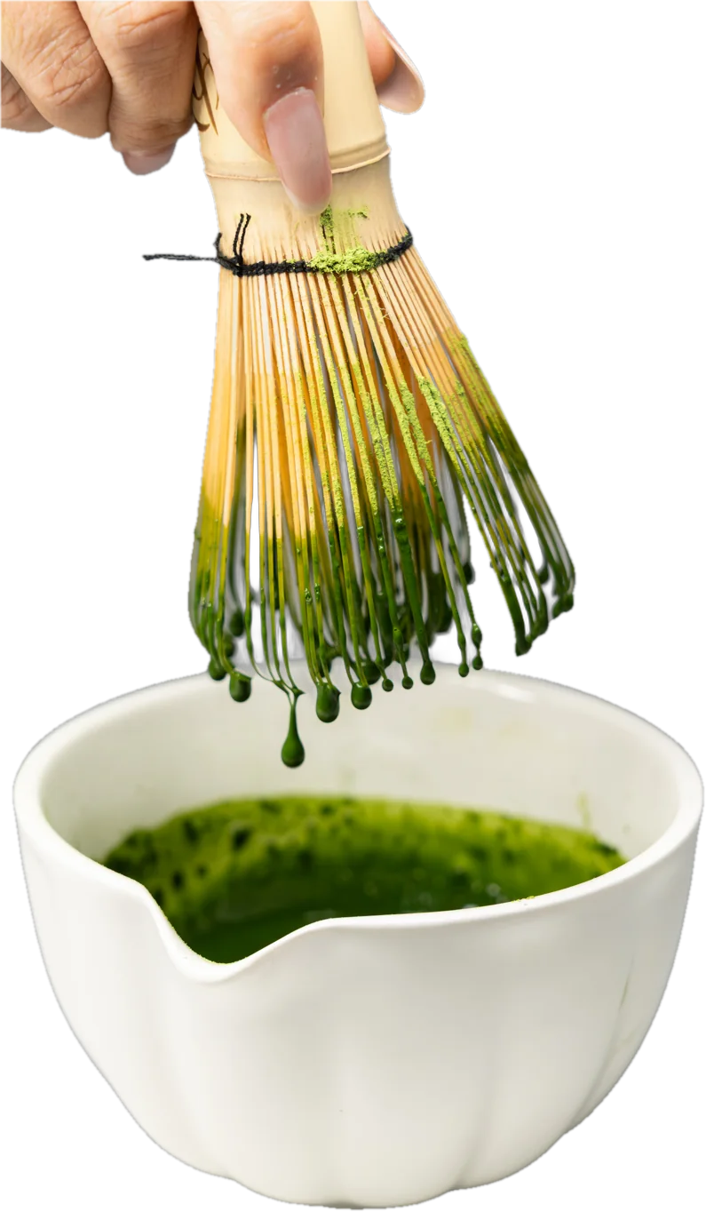 Matcha tropft vom Bambusbesen in eine weiße Schale
